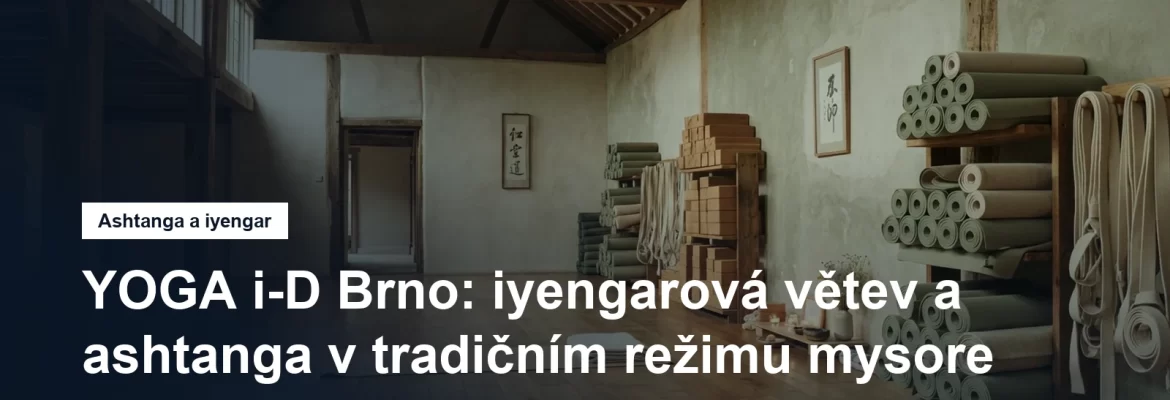 Jógový sál s vysokým stropem, podložkami a pomůckami u zdi, bez lidí